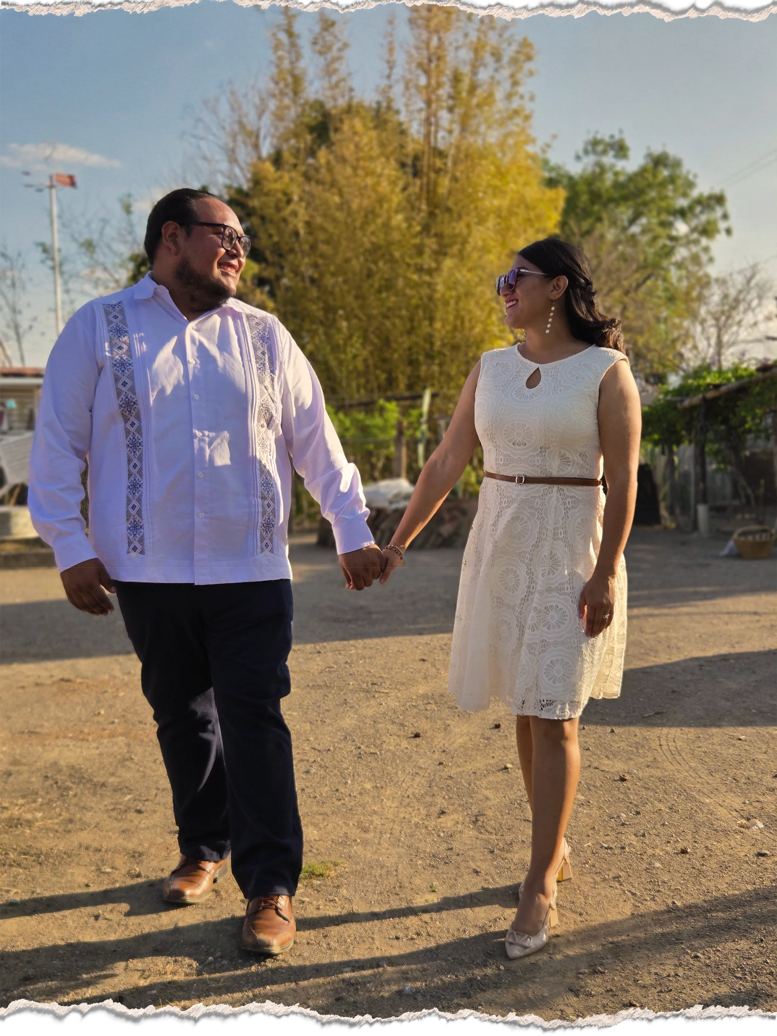 Analy y Efraín caminando tomados de la mano durante una sesión al atardecer